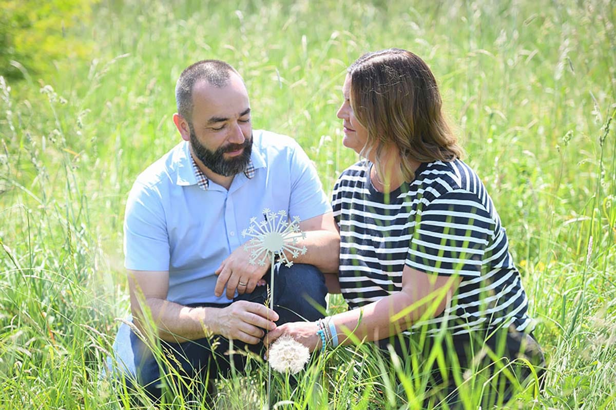 Luca Atzori and Wife crouch down in a field of green grass