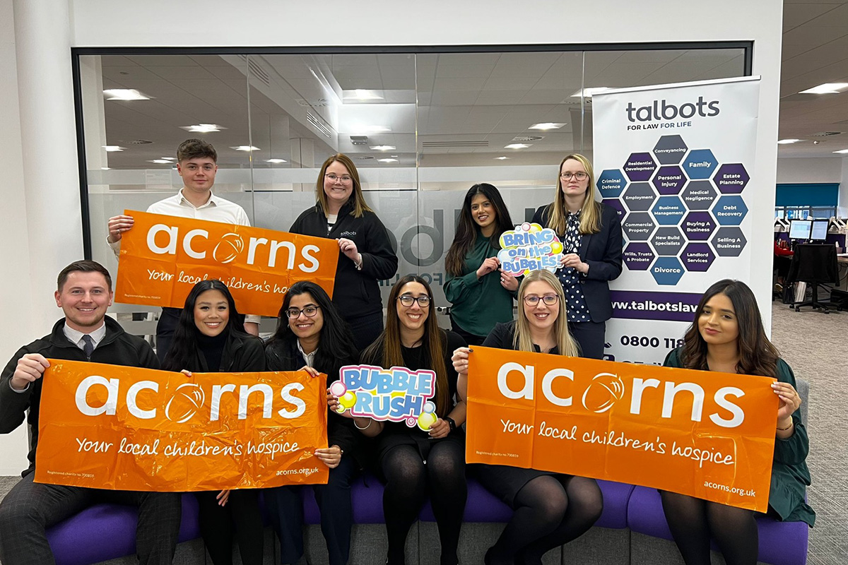 Talbots Law Firm Staff holding up Acorns banners to celebrate the money they raised at Bubble Rush