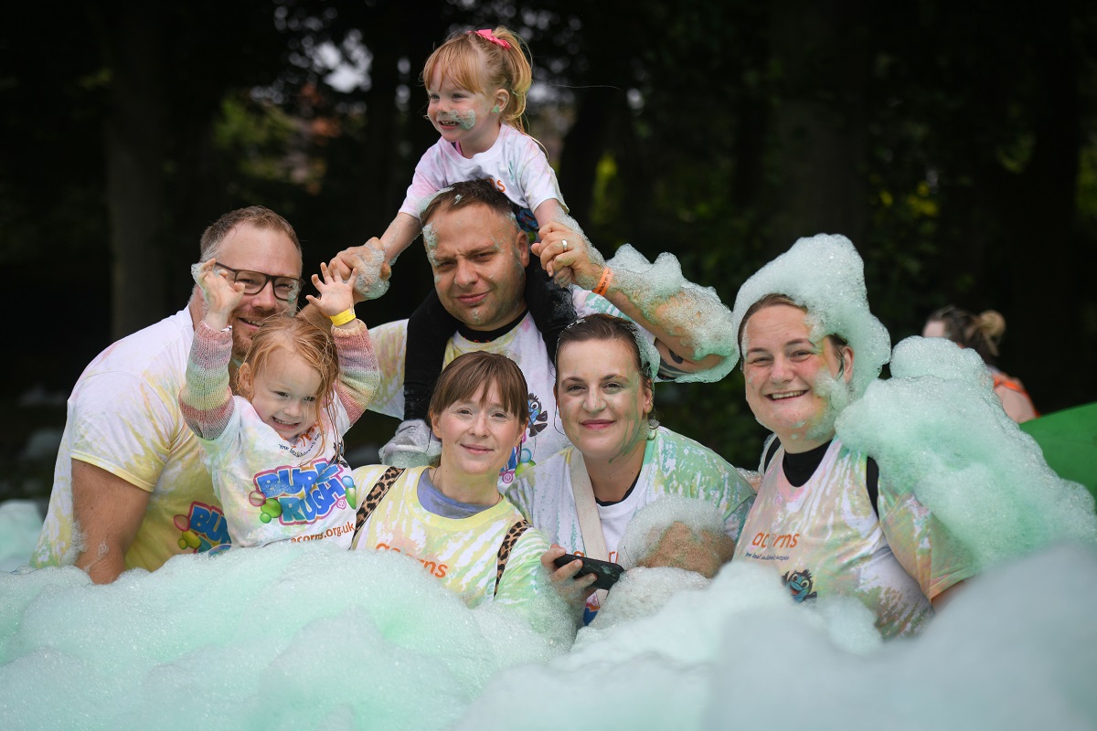 A family or group of friends all posing together surrounded by green bubbles from the Acorns Bubble Rush family fun event