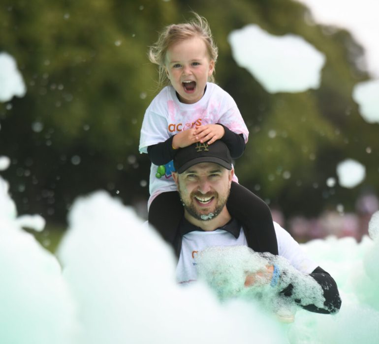 Dad and daughter having fun in the green bubbles at Acorns Bubble Rush