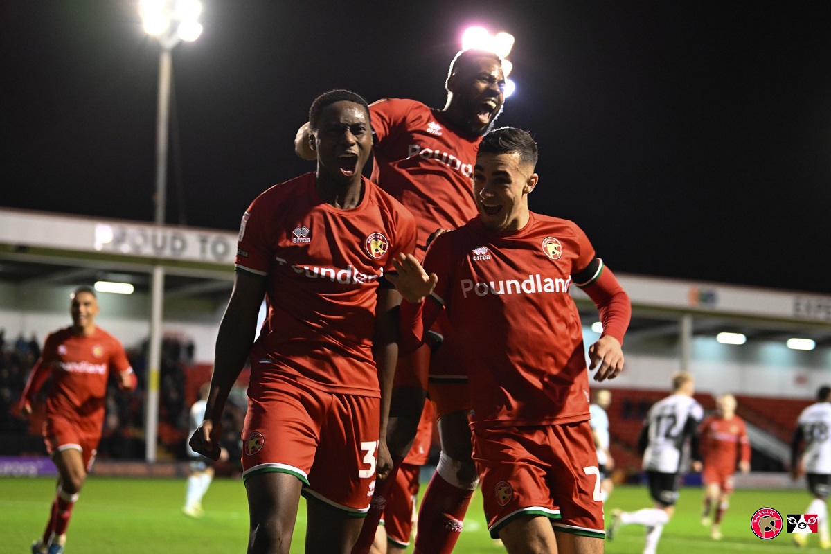 Three Walsall FC players celebrating on the pitch