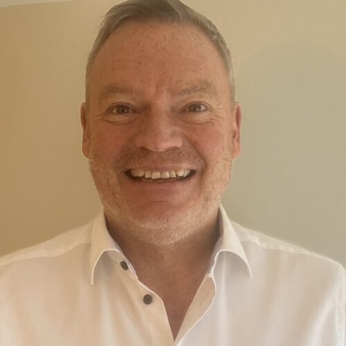 A man in a white shirt grins at the camera