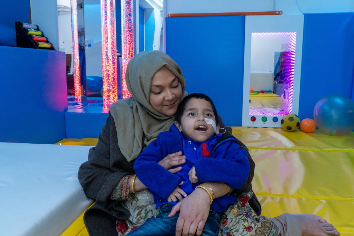 A mother holding a young boy who has a tube into his nose.