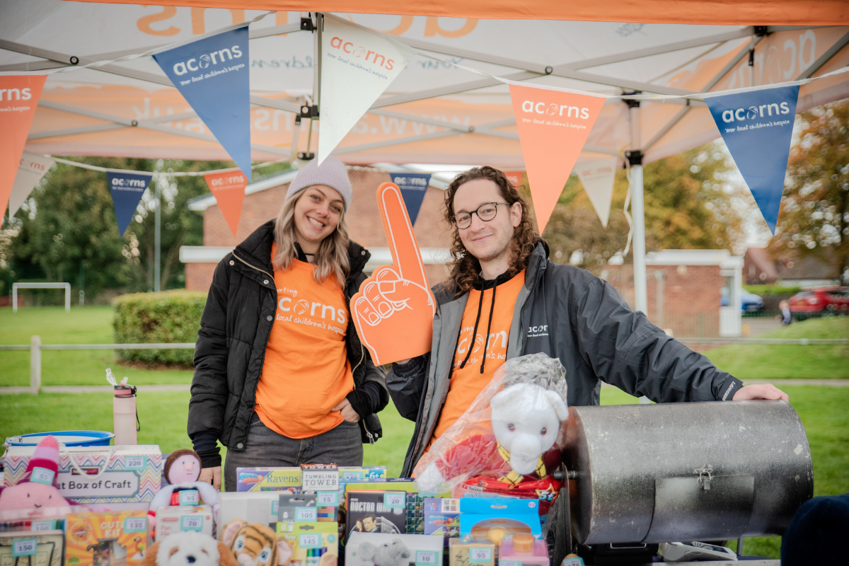 Shenstone 10k Fun Run Two people at a stand filled with toys, wearing Acorns branded t-shirts.