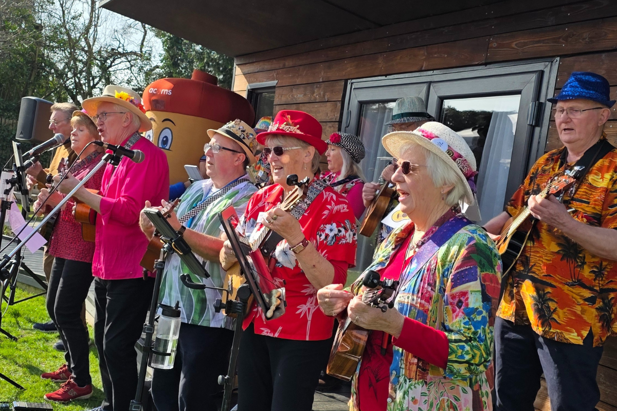 A group of people wearing colourful outfits and sunglasses holding ukuleles.