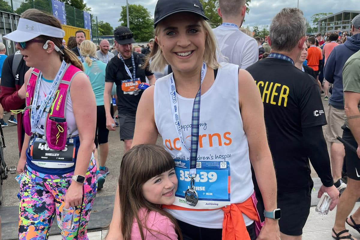 Edinburgh Marathon A woman wearing an Acorns running vest and medal hugging a young girl.