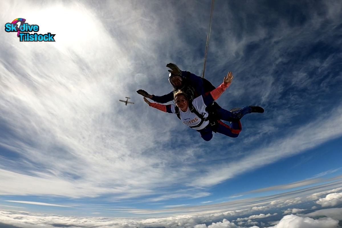 June Skydive A skydive instructor and woman wearing an Acorns top free-falling in the sky.