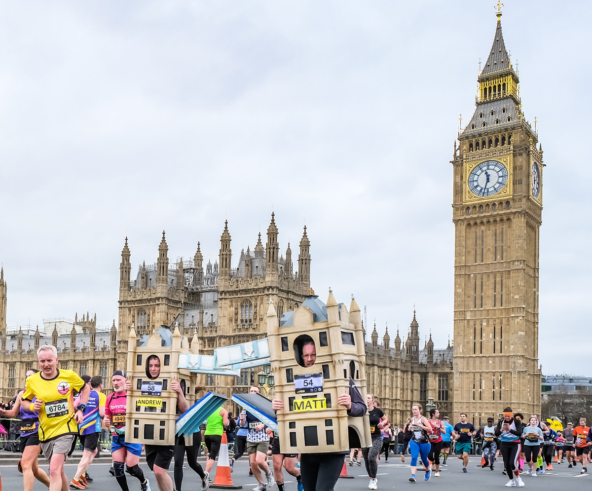 Runners pass by the Houses of Parliament and Big Ben on the London Landmarks Half Marathon. Two runners are dressed as Tower Bridge