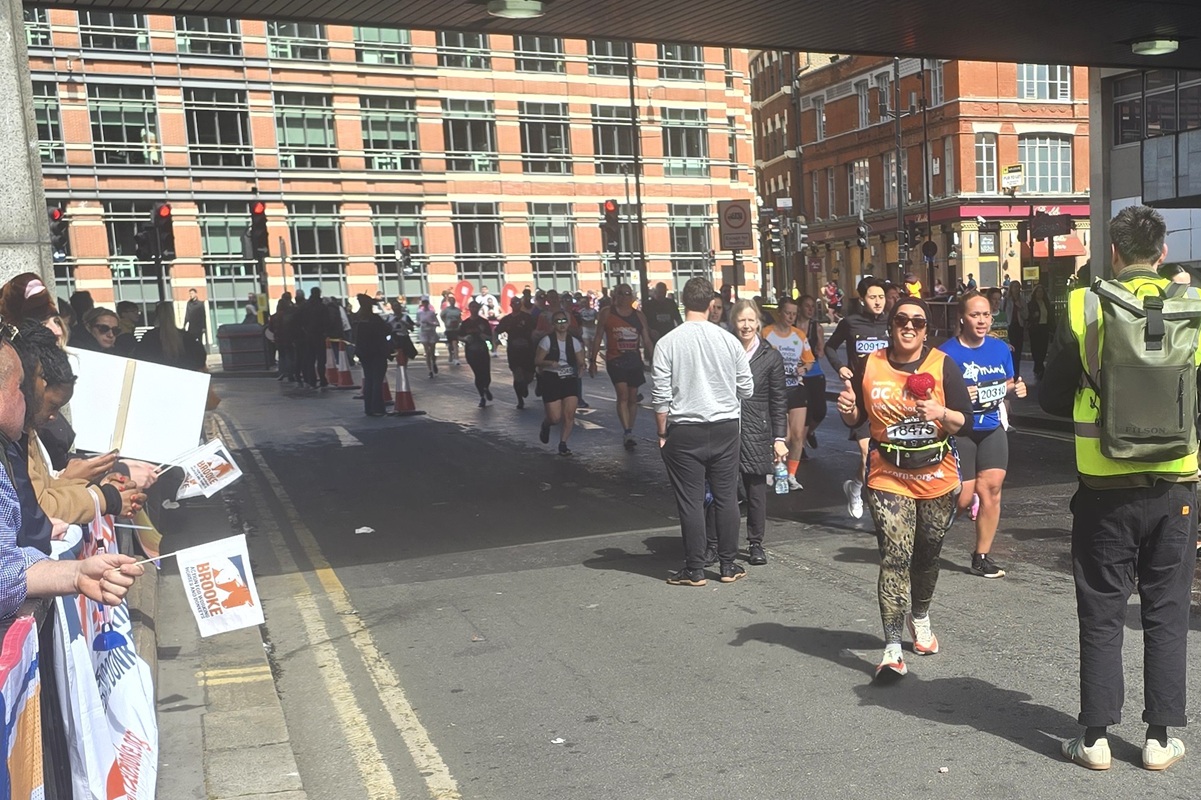 A runner in an Acorns running vest gives a thumbs up as they run the London Landmarks Half Marathon
