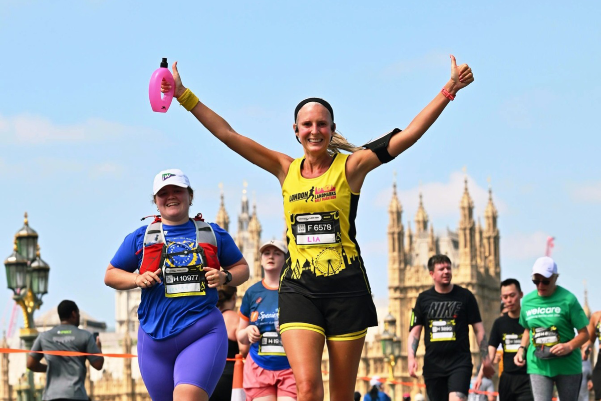 A woman running with her arm sin the air at the London Landmarks Half Marathon.