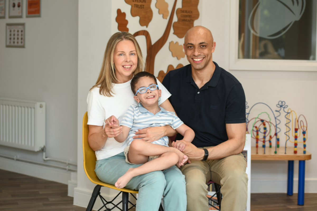 A woman, a man and their son sat on chairs all smiling.