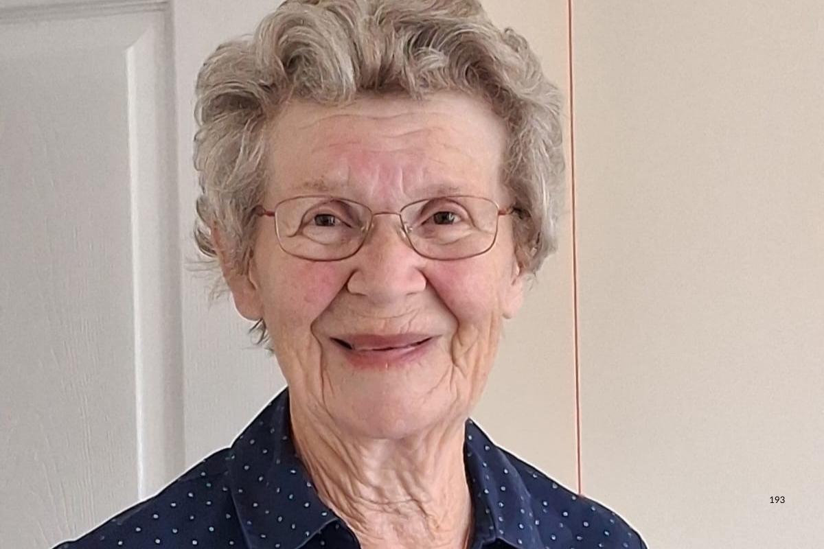 A close up headshot of an elderly woman smiling.