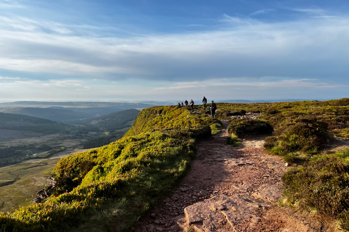 People in the distance walking along a path on Pen y Fan peak.