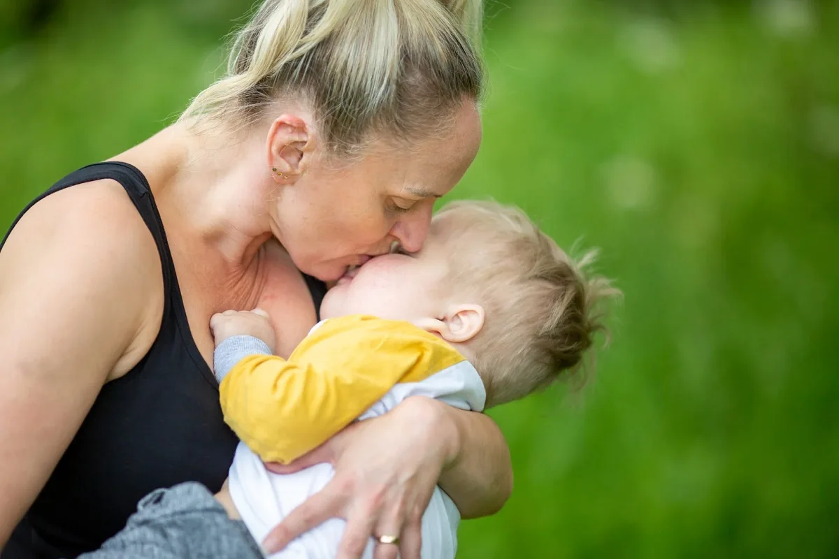 A woman kisses and cuddles a little boy