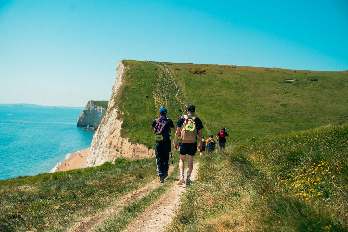 Two people with their back to the camera walking along a path on the Jurassic Coast.