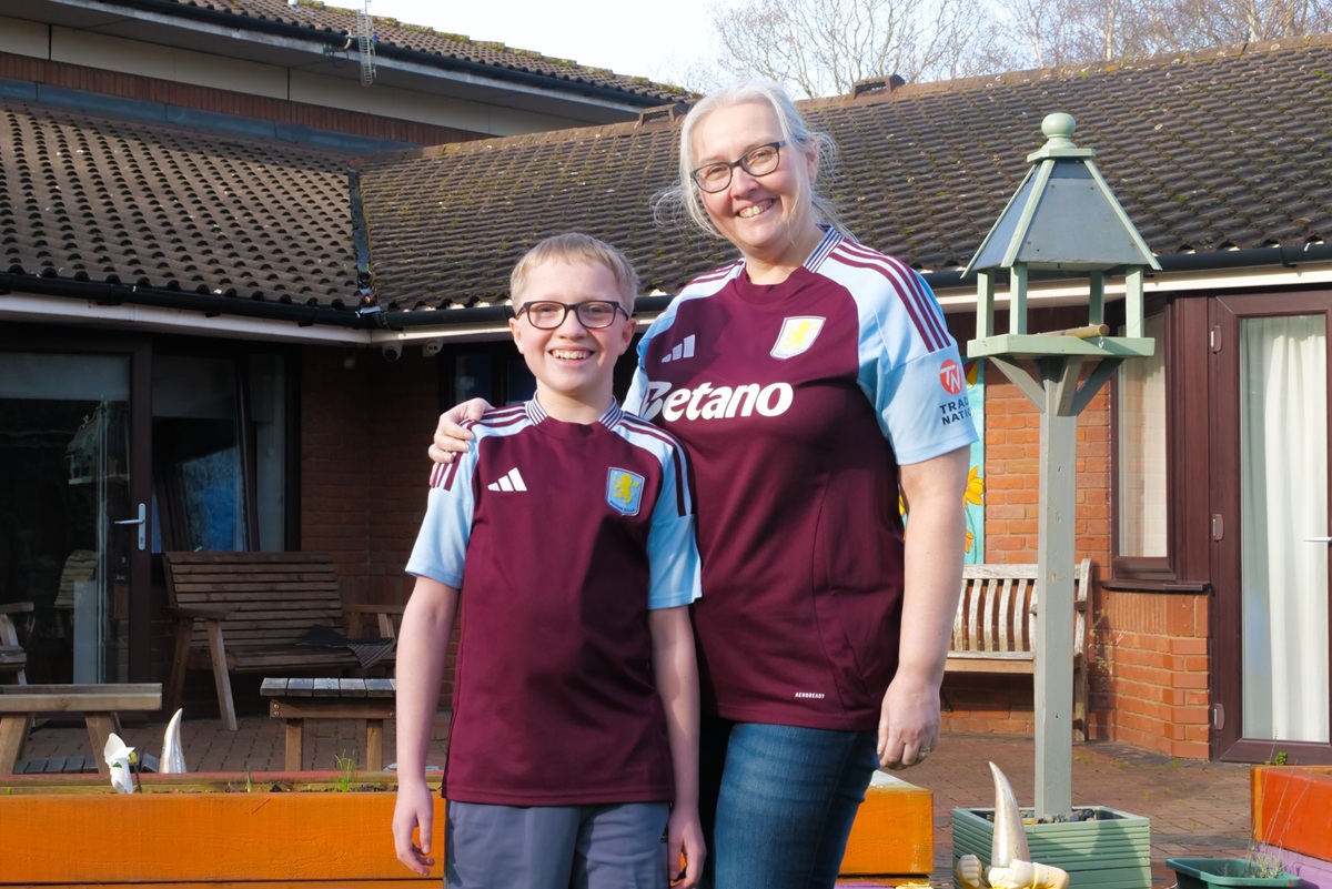 A woman and boy wearing Villa tops stand in the garden of an Acorns hospice