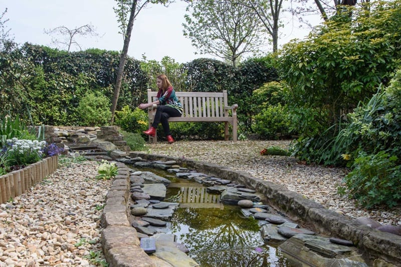 Memorial garden with a woman sat on a bench in the background.
