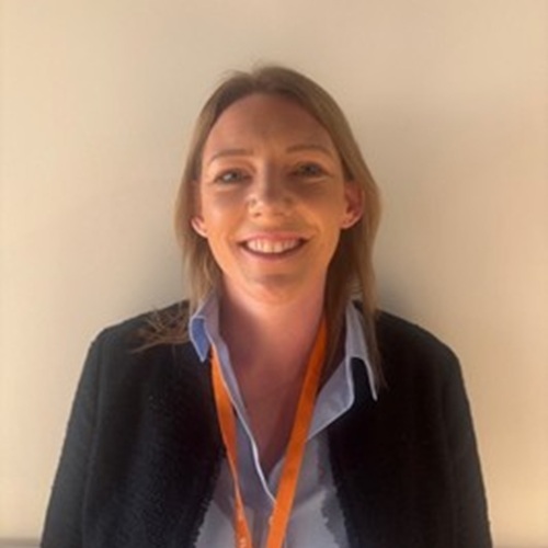 A smiling woman wearing an Acorns lanyard