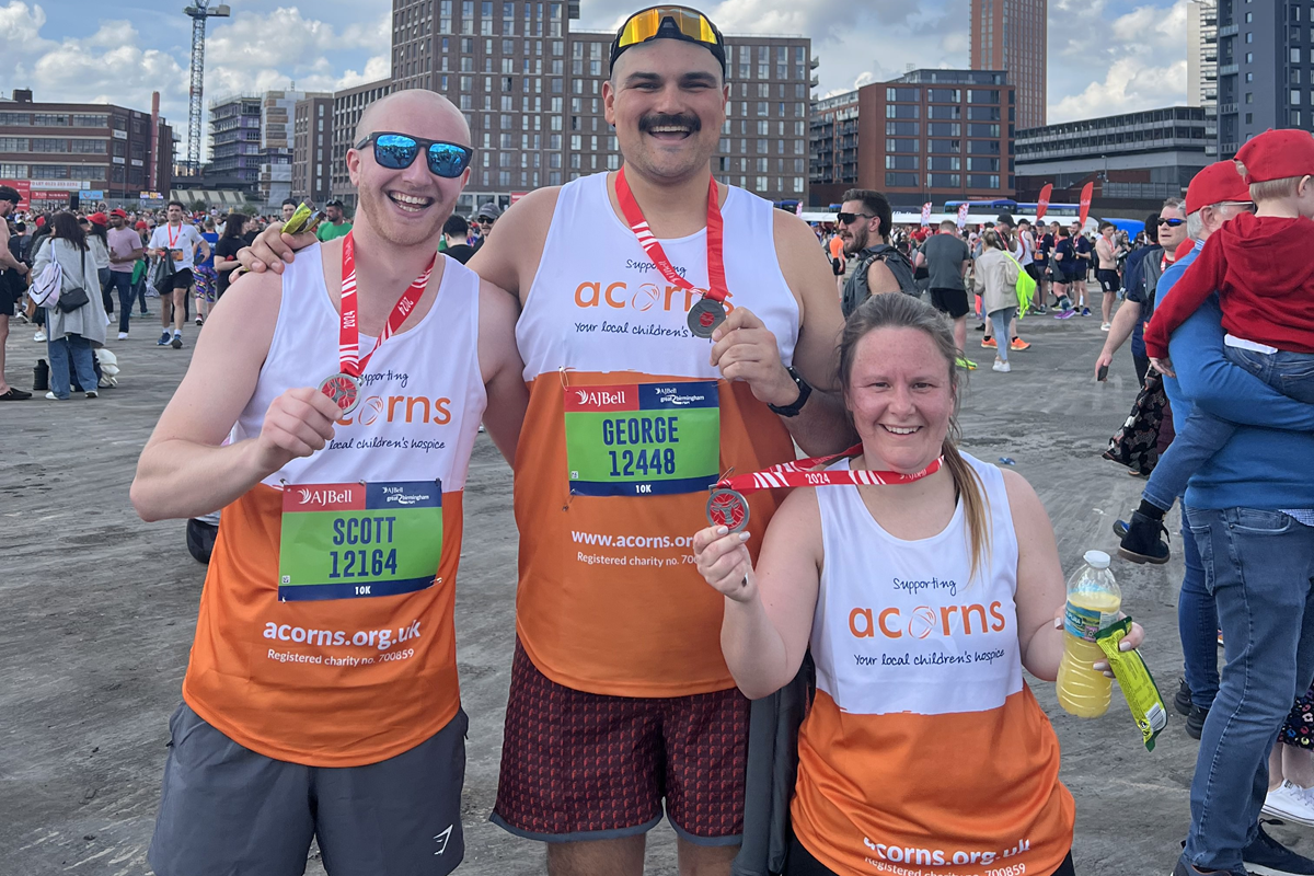 A group of people with Acorns running vests and Great Birmingham Run medals