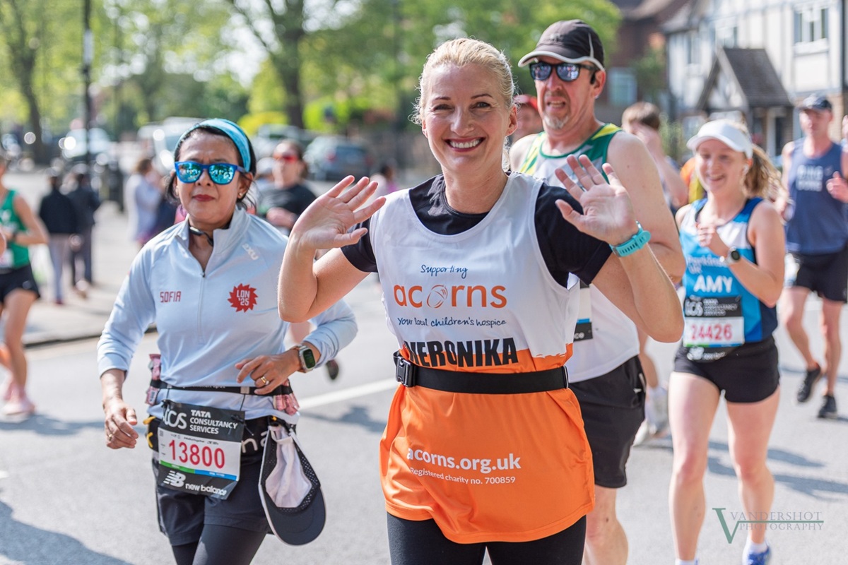 Smiling runner wearing an Acorns running vest in the London Marathon