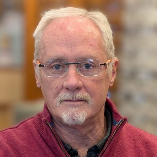 An older man who has glasses and is wearing a red fleece.