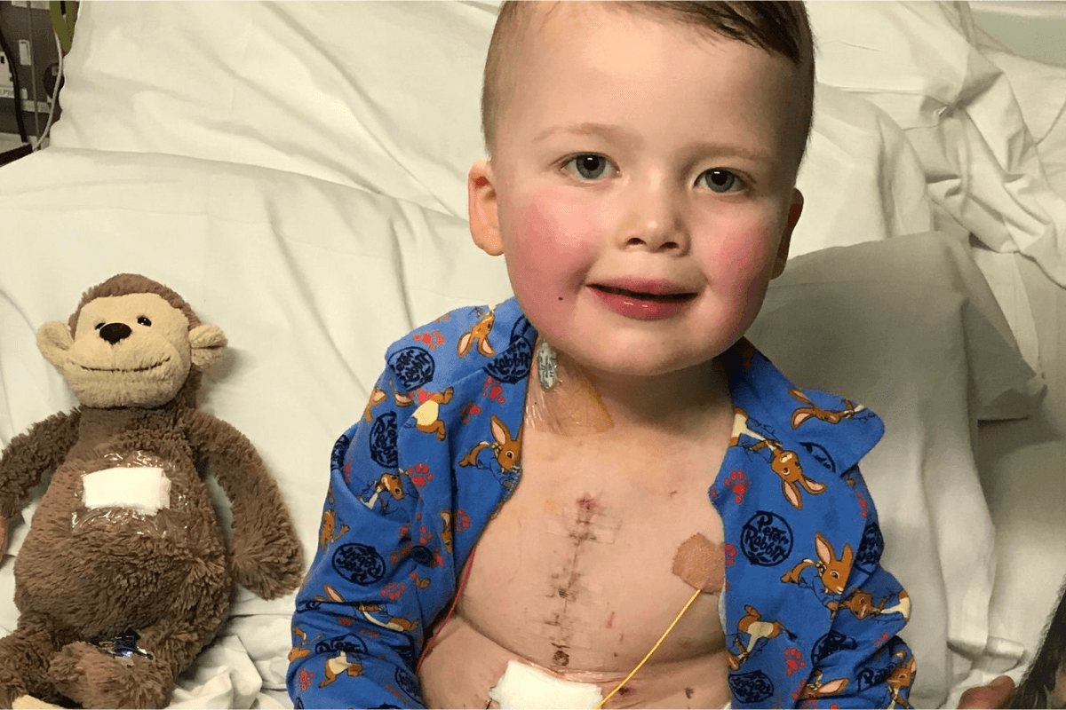 Young boy in a hospital bed with bandages and tubes after an operation.
