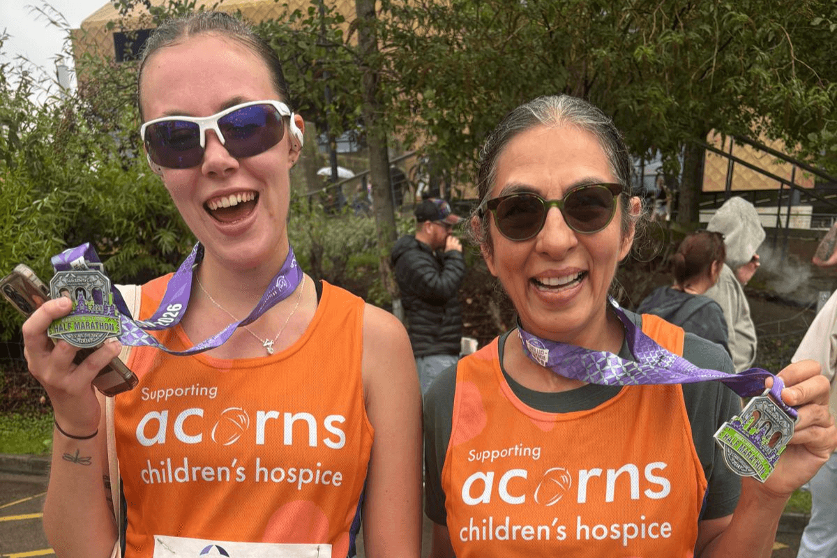 WCR 27 Two women wearing Acorns running vests and sunglasses, both holding a Worcester City Runs medal.