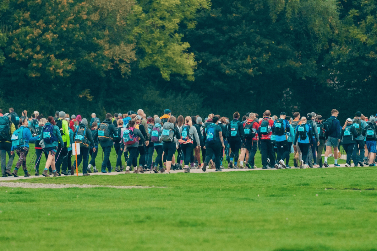 Kent Downs 50 A long line of challengers walking down a path through a field.