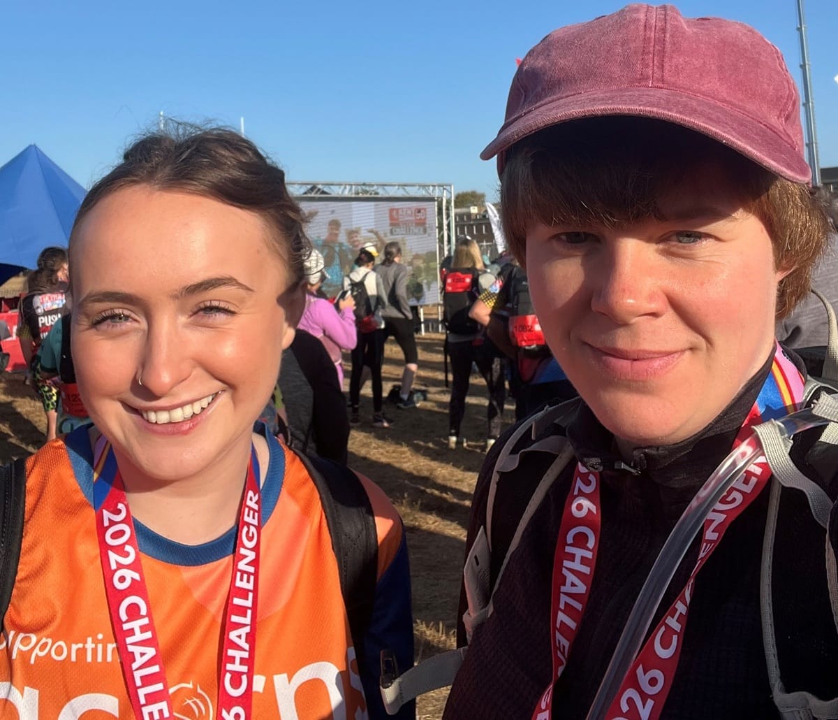 Two Ultra Challenge Summer Walk participants with medal round their necks, smiling in the sunshine. One is wearing an Acorns top