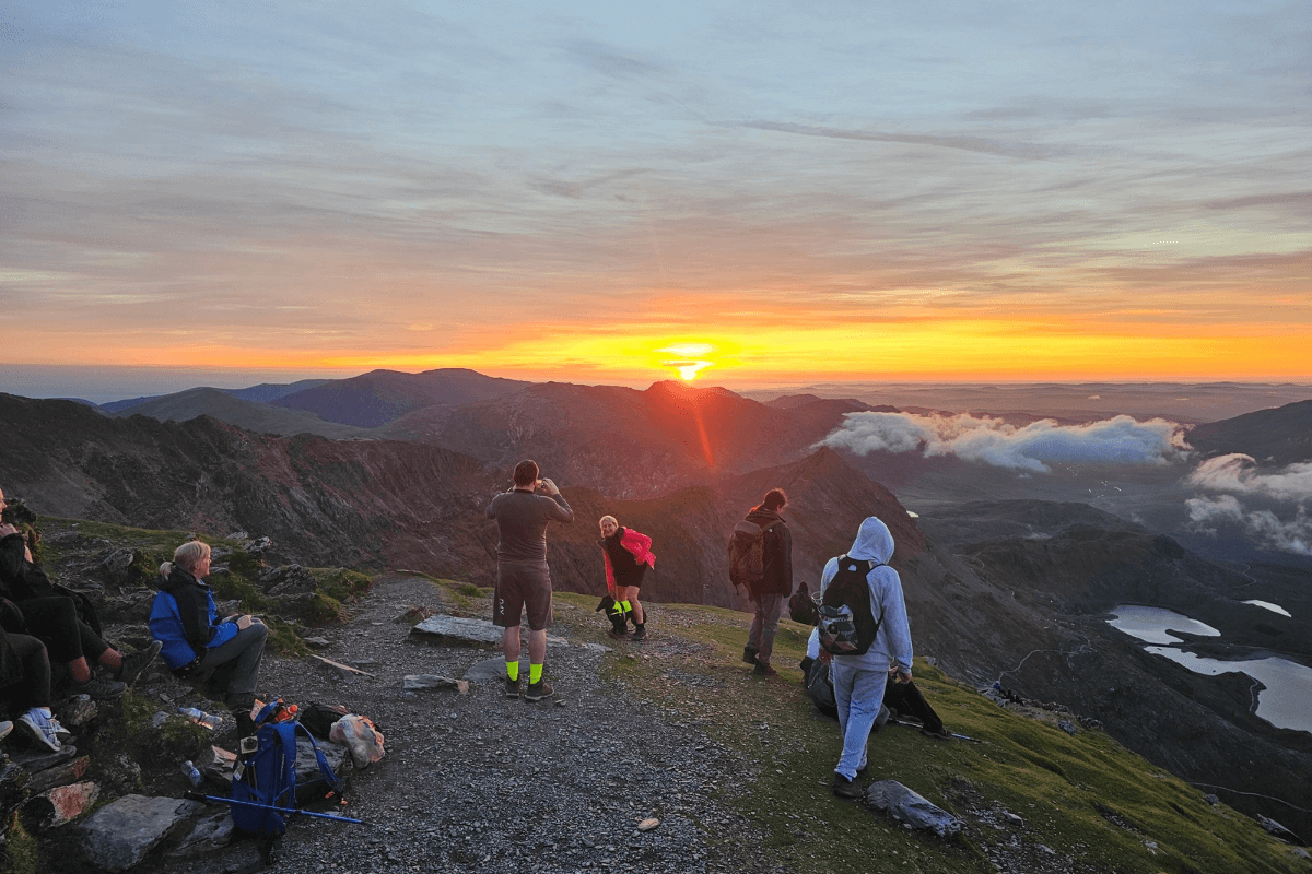 Sunrise trek A group of people watching the sunrise at the peak of Snowdon.