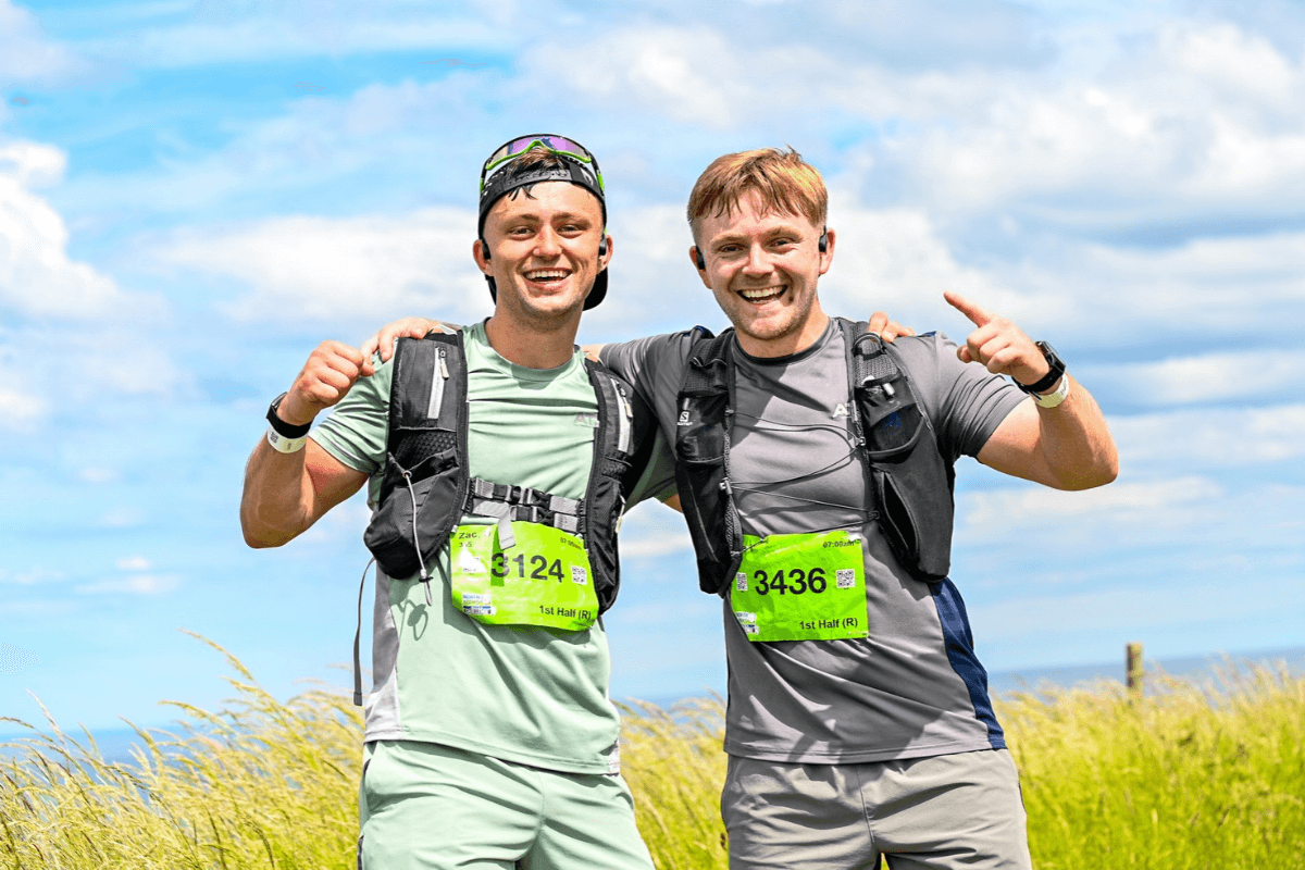 The Borders Two men with their arm round each other smiling, both wearing running vests.