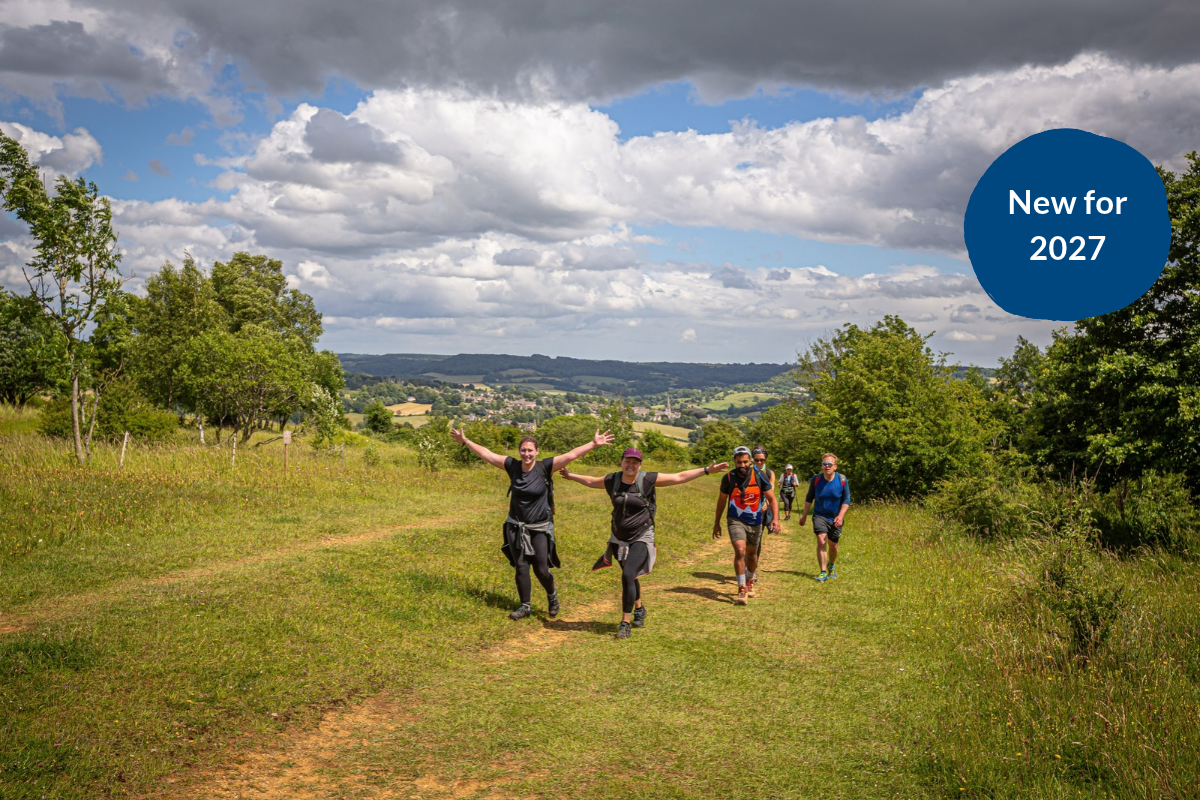 Four people walking up the Shropshire Hills. The two people at the front both have their arms outstretched to the side.
