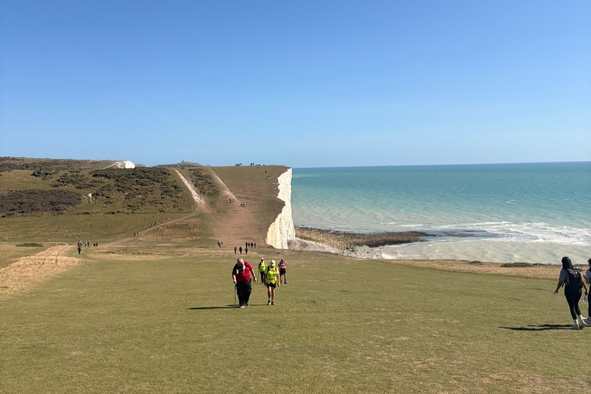 A cliffside coast with a number of challengers walking in the distance as part of the South West Coast Ultra Challenge.